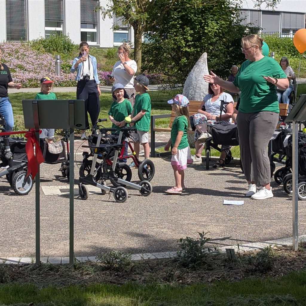 Eine Gruppe von Kindern und Erwachsenen versammelt sich im Freien vor einer modernen Gebäudeanlage.